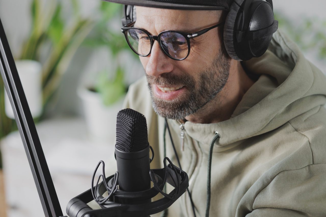 records audio content or podcast for his blog a serious adult european man in a baseball cap